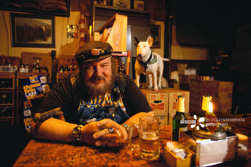 摩托车手坐在桌旁喝啤酒图片素材