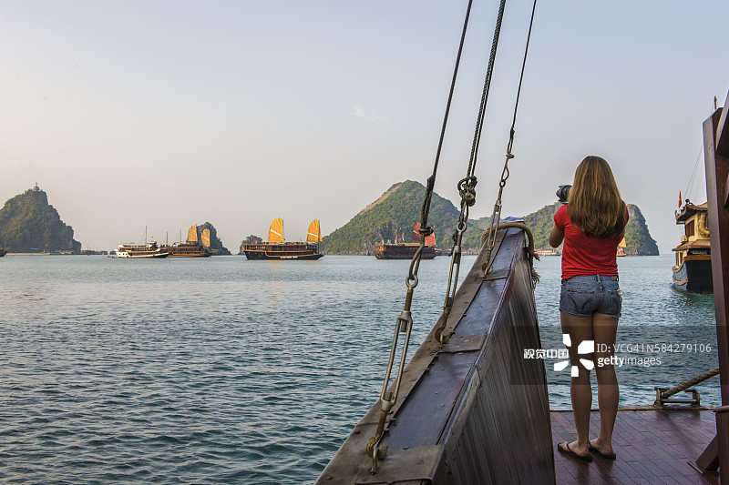年轻女子在下龙湾拍摄帆船图片素材