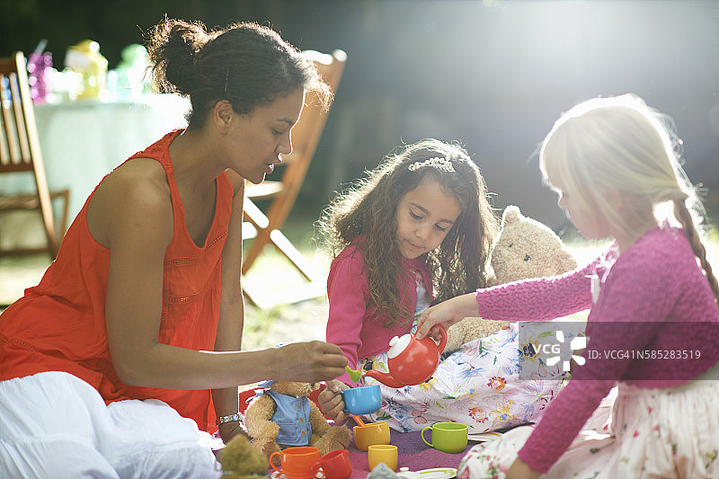 母亲和两个女孩在花园生日派对上玩野餐图片素材