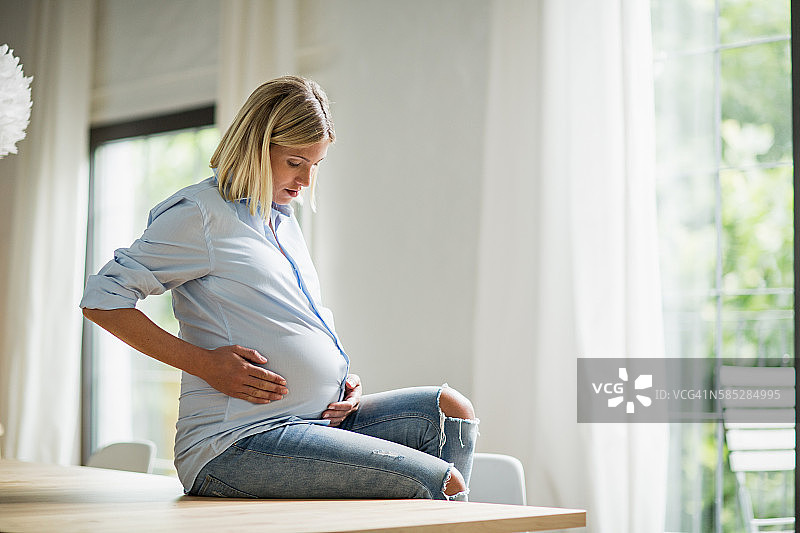 坐在厨房桌子旁的足月孕妇图片素材