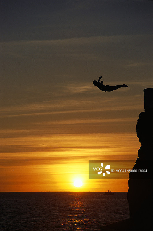 日落时分的悬崖跳水者图片素材