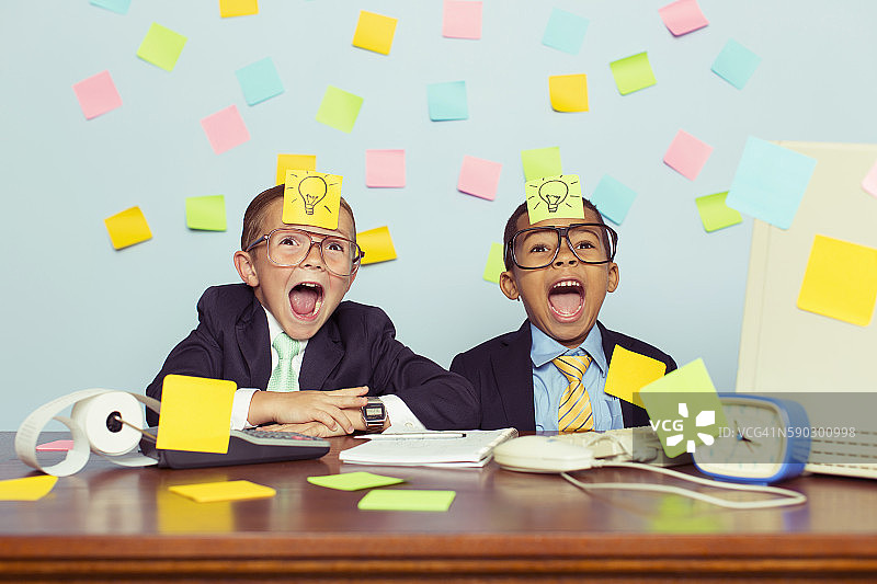 两位年轻的商人坐在贴满便利贴的桌子旁图片素材