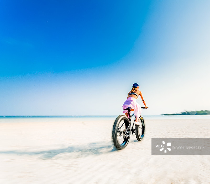 年轻女人骑着胖胎自行车在海滩上锻炼图片素材