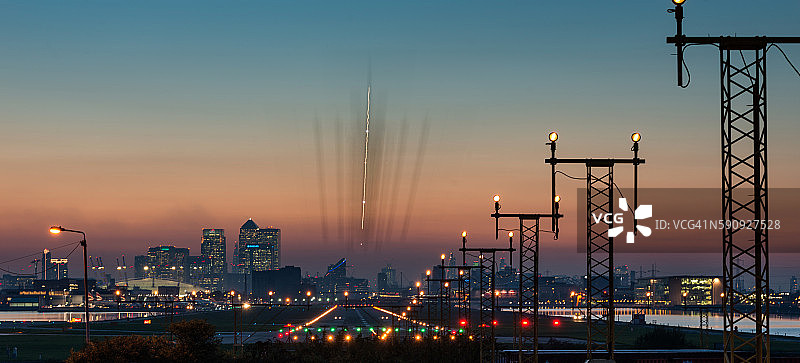 飞机在城市机场日落时降落，背景是金丝雀码头和千禧巨蛋（O2体育馆）图片素材