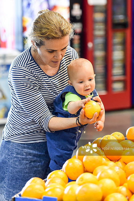 中年妇女和她的婴儿一起购买水果图片素材