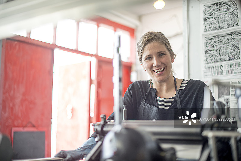 女印刷工在工作室使用传统凸版印刷机图片素材