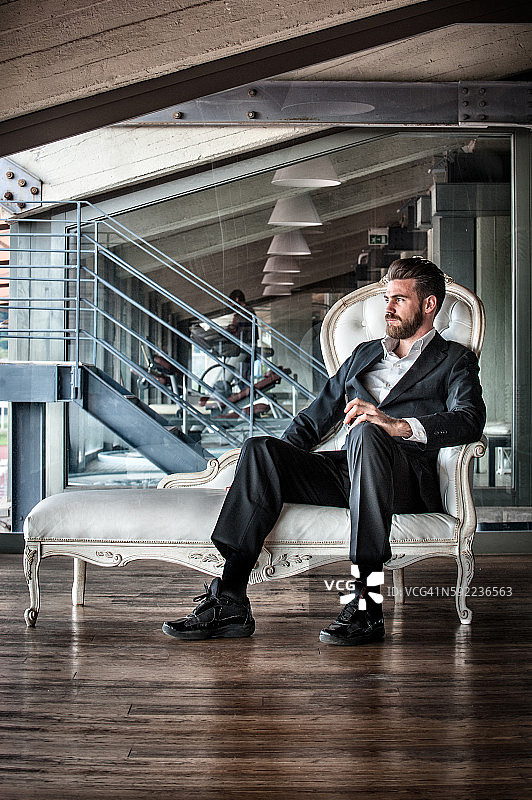 中年男人穿着西装坐在躺椅上，看向远方图片素材