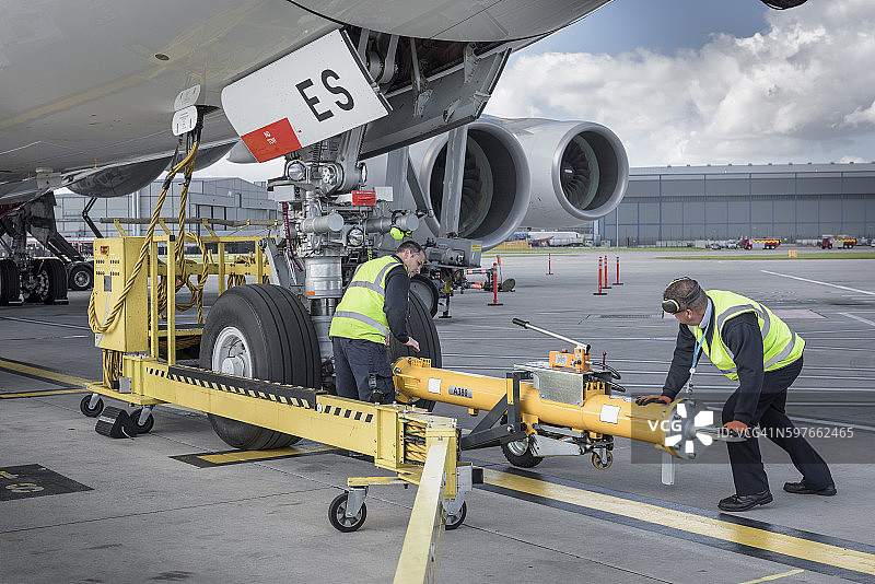 机场地勤正在将牵引杆固定到A380飞机上图片素材