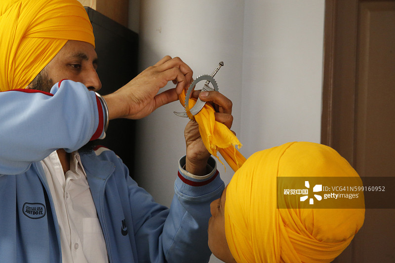 法国博比尼锡克教谒师所：神殿，成人在Hola Mohalla节（新年）为男孩系头巾图片素材