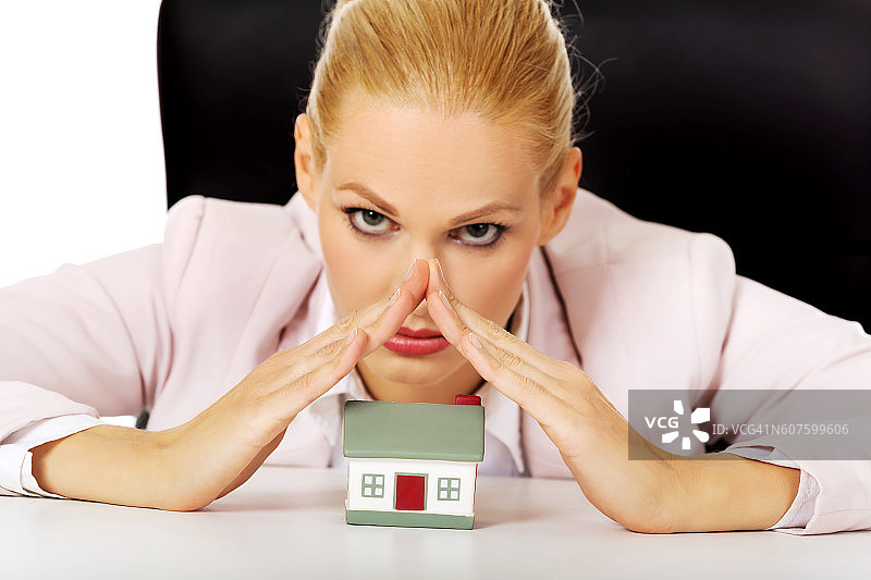商务女人坐在办公桌后，带着房屋模型图片素材