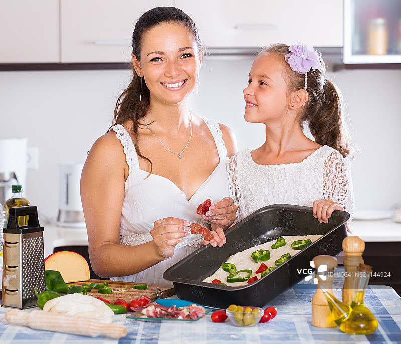 家庭主妇和女儿一起烹饪披萨图片素材