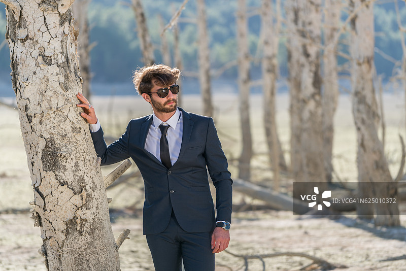 站在龟裂土地上的商务男士时装模特图片素材