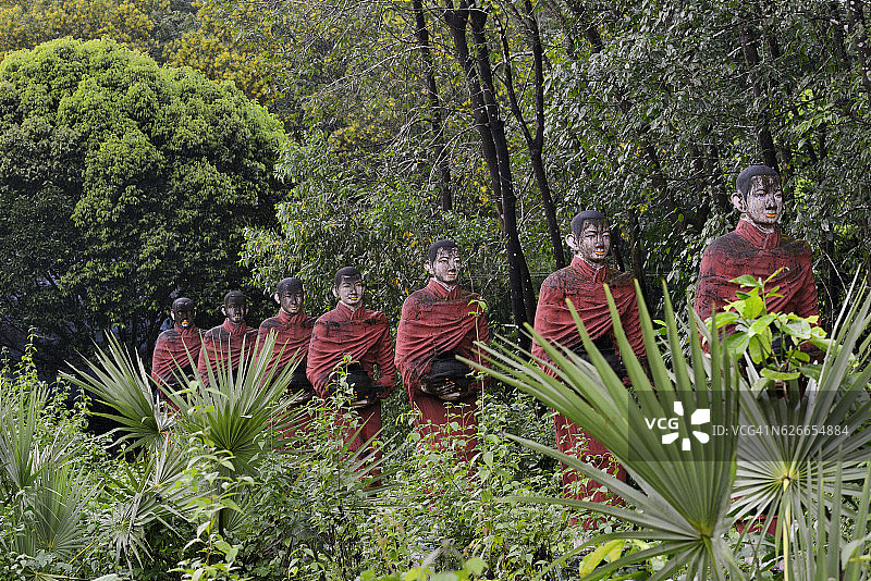 一排手持乞讨钵的和尚雕像图片素材