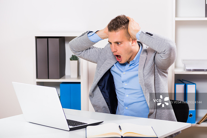 惊慌地看着笔记本电脑的商人图片素材