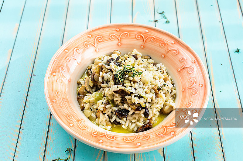 木制蓝绿色背景上的美味牛肝菌烩饭图片素材