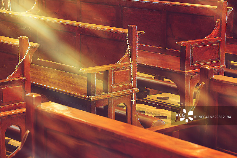 教堂内的木制长椅和阳光下的念珠图片素材