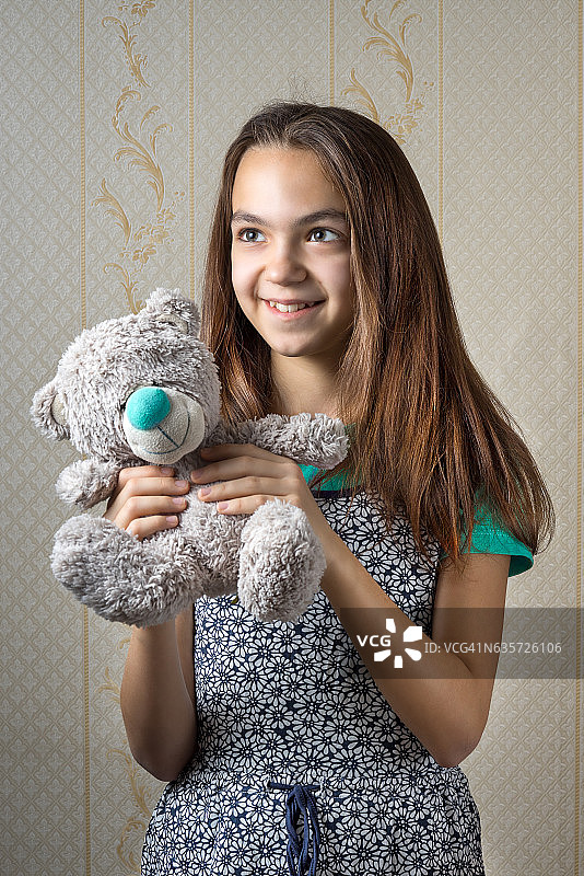 快乐的11岁女孩抱着泰迪熊图片素材