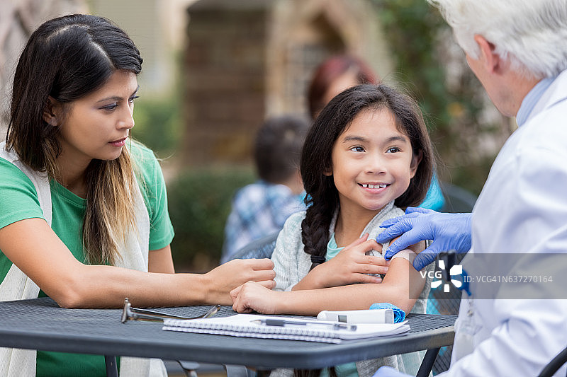 在免费诊所接受免疫接种后微笑的小女孩图片素材