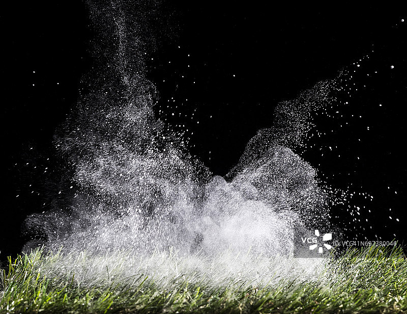 白色粉末颗粒在黑色背景上爆炸图片素材