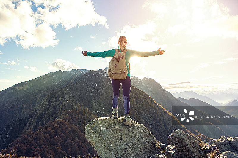 年轻女子徒步登上山顶，张开双臂图片素材