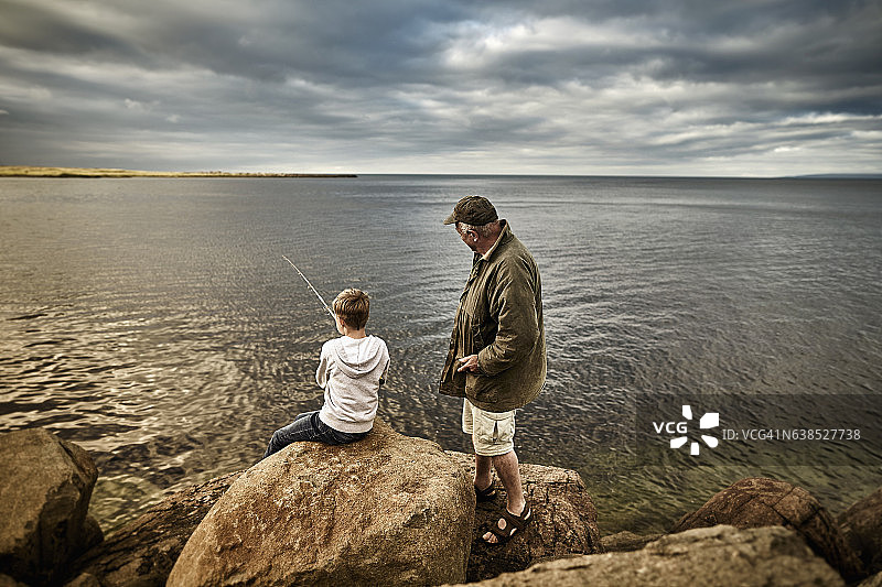 英国苏格兰：男孩和年长男人一起钓鱼图片素材
