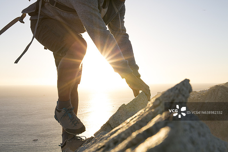 男性徒步旅行者穿越山顶岩石，俯瞰大海图片素材