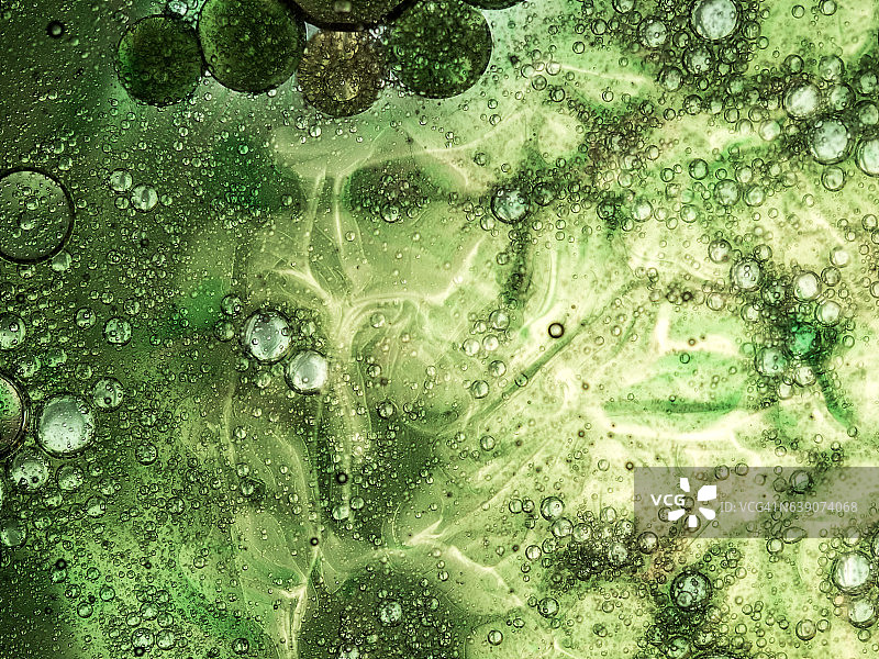 气泡和油滴在绿色和黄色背景上形成圆形纹理图片素材
