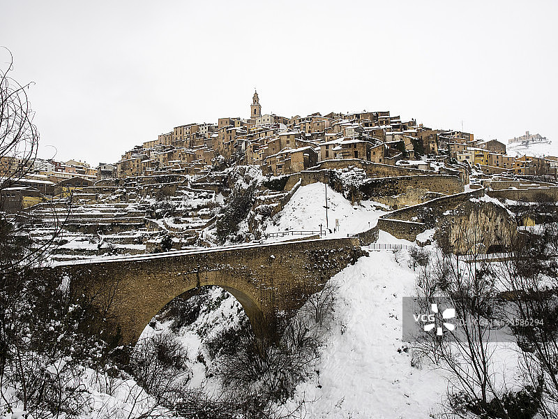 中世纪建筑的昔日居民在冬季被雪覆盖，坐落在一座有通道桥的山丘上图片素材