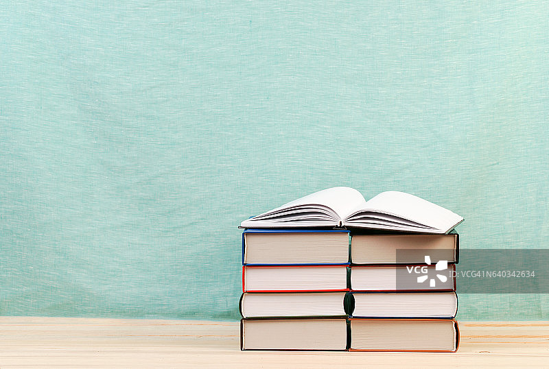 打开的书本，堆叠在木桌上的精装书。图片素材