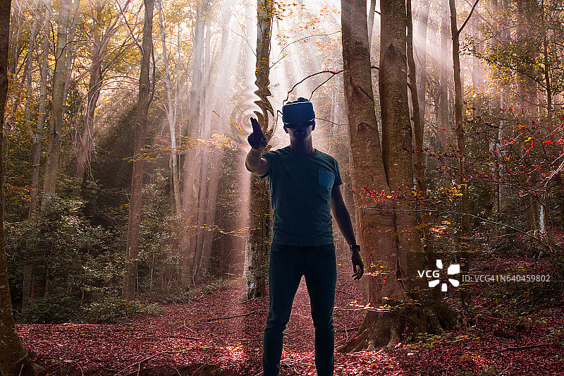 男子体验VR头显，沉浸在美丽的自然森林中图片素材