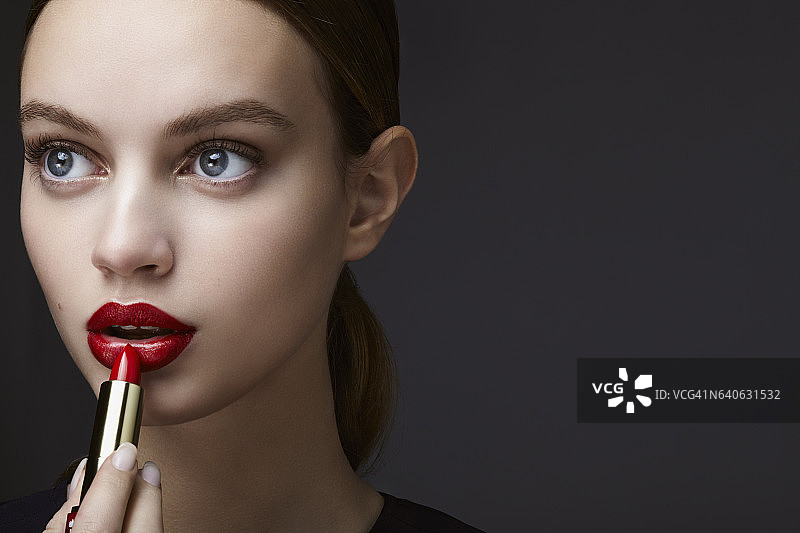 年轻女性涂口红的化妆品肖像图片素材