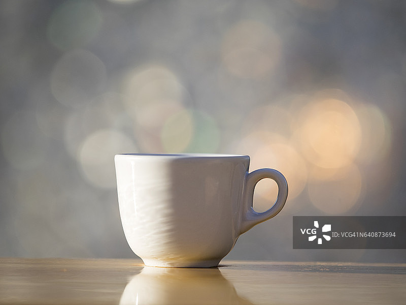 阳光照射下，白色瓷杯中的浓缩咖啡图片素材