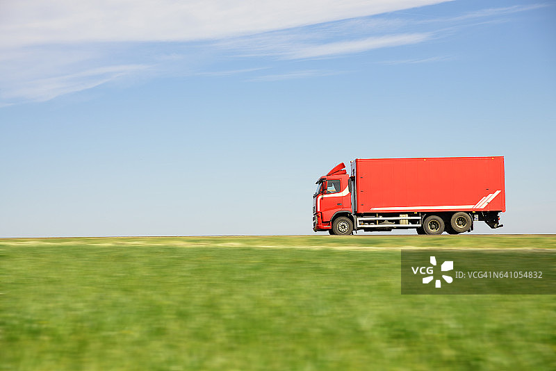 红色卡车穿过田野图片素材