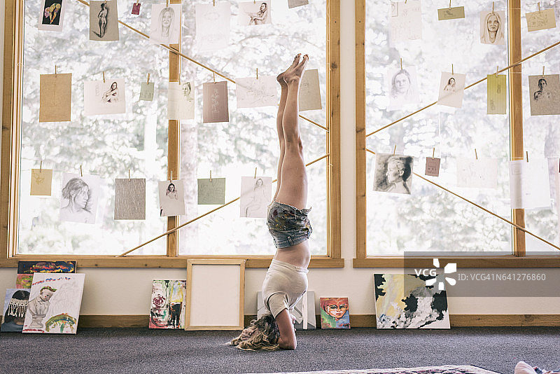 年轻女艺术家在工作室里倒立图片素材