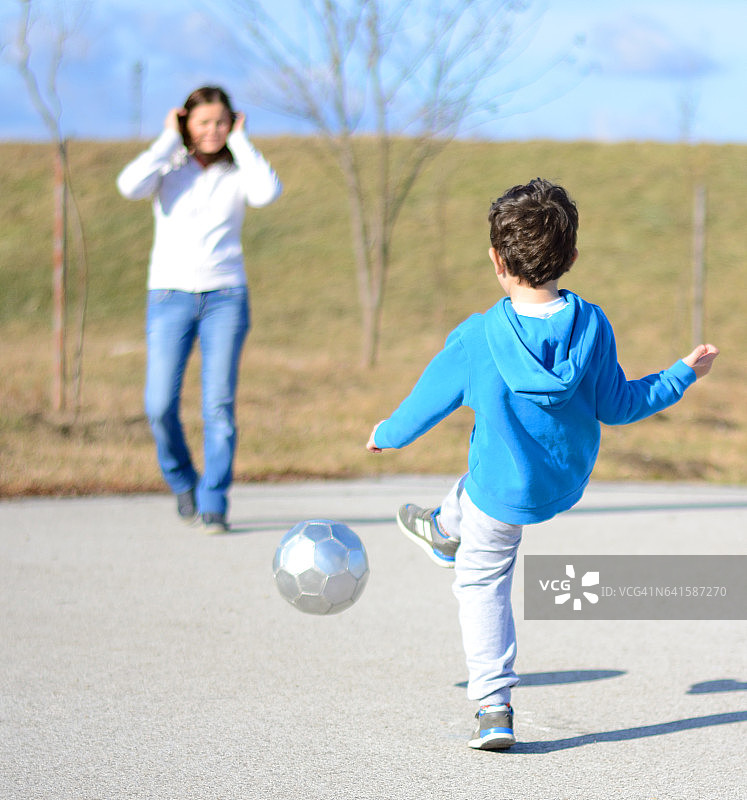 妈妈和儿子在体育场踢足球图片素材