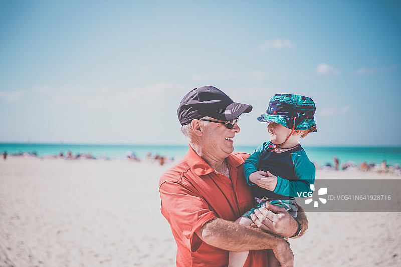 古巴热带海滩上抱着男婴的祖父图片素材