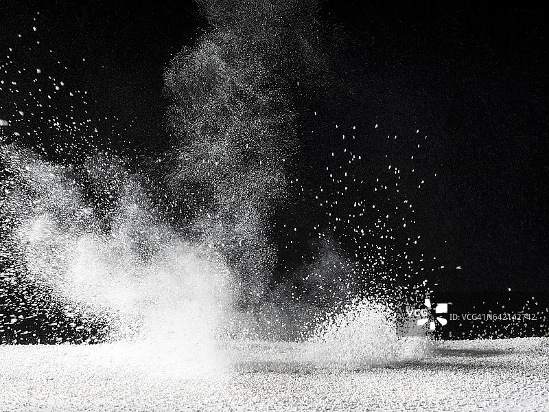 白色粉末颗粒在冲击作用下漂浮在空气中的黑色背景图片素材