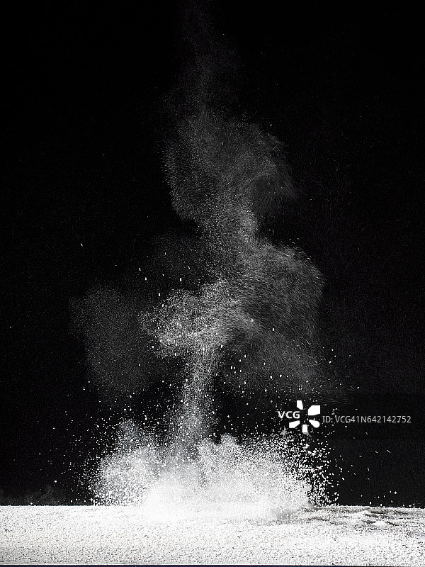 白色粉末颗粒在冲击作用下漂浮在空气中的黑色背景图片素材