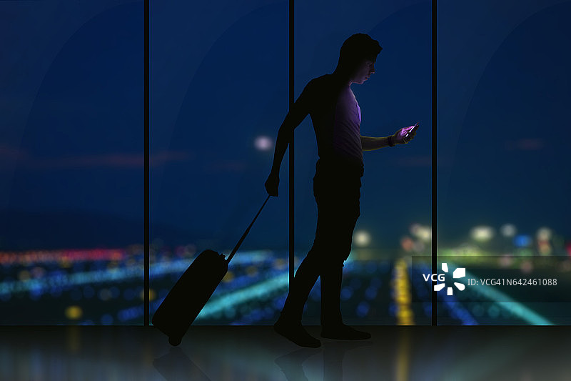 男子在机场夜晚用智能手机查看航班信息图片素材