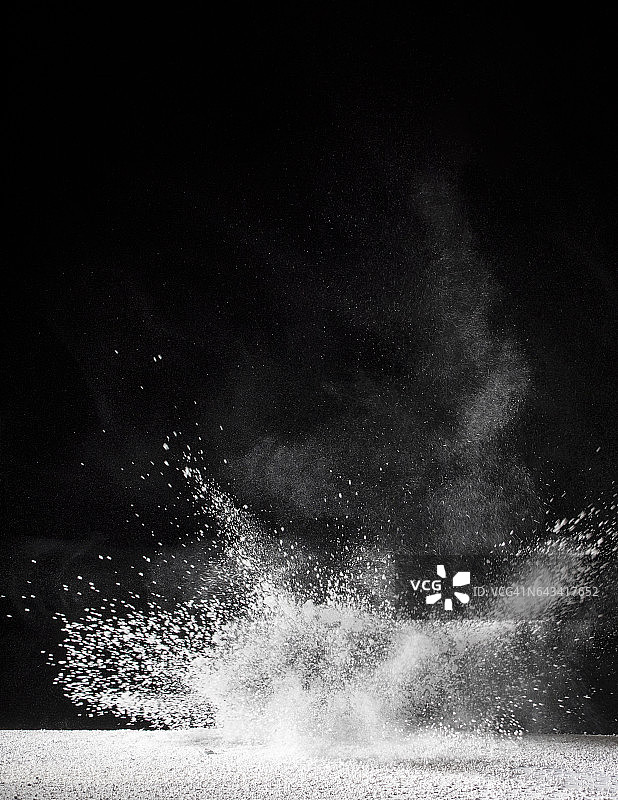 白色粉末颗粒在冲击作用下漂浮在空气中的黑色背景图片素材