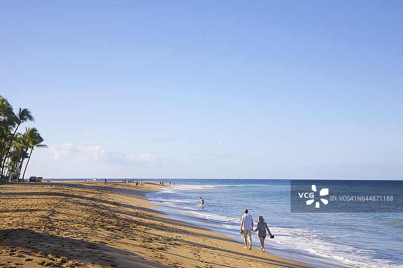 情侣在沙滩上牵手散步图片素材