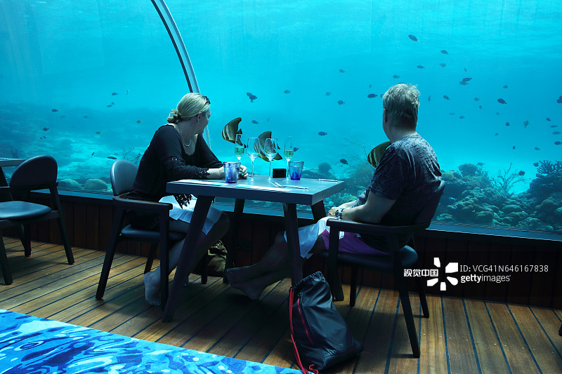 情侣在世界最大的全玻璃海底餐厅（芙拉瓦丽）用餐时观赏鱼类图片素材