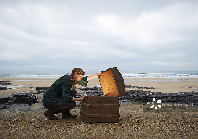 在荒凉的海滩上查看宝箱内部的女人图片素材