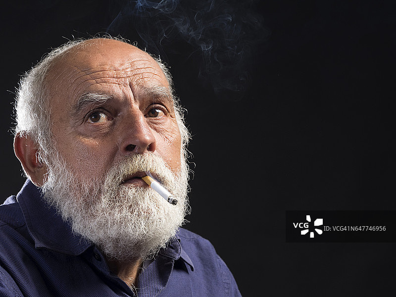 在烟雾环境中吸烟的白胡子成年男人肖像图片素材