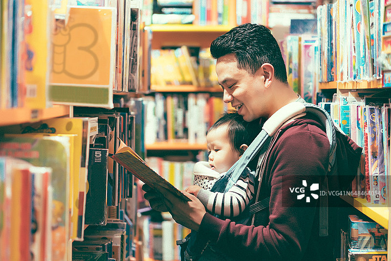 9个月大的中国男婴在书店与父亲一起快乐地读书图片素材