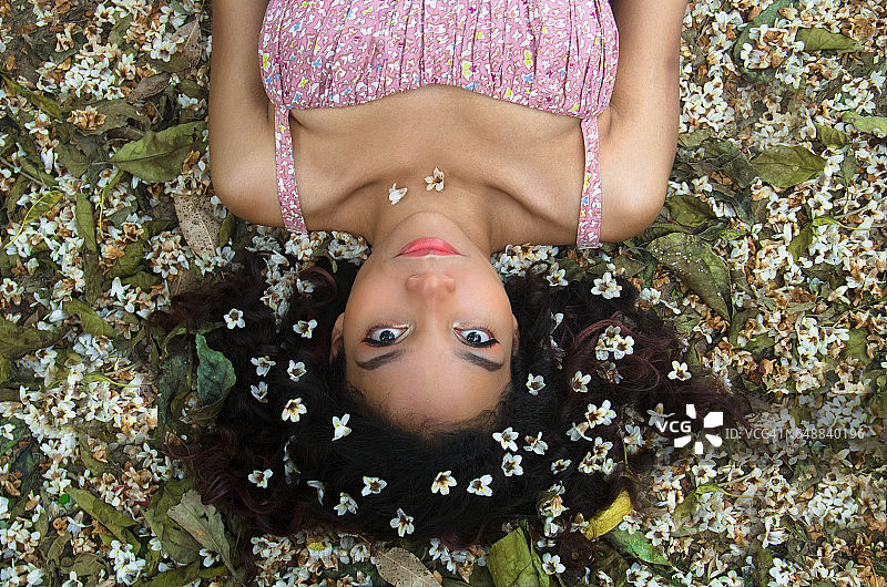 年轻女子躺在鲜花草地上的人物肖像图片素材