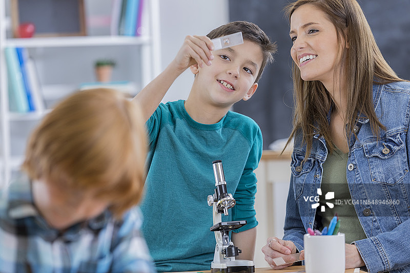 小学生在学校看显微镜载玻片图片素材