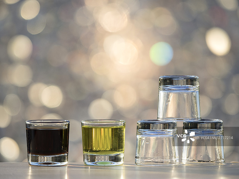 小酒杯，一个满杯，另一个空杯，被阳光照亮图片素材