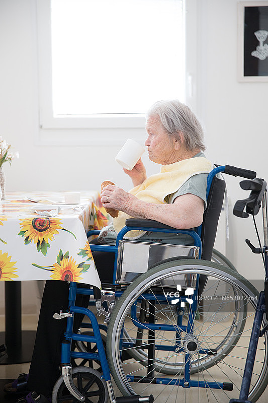 在护理中心坐轮椅等待早餐的老年女人图片素材