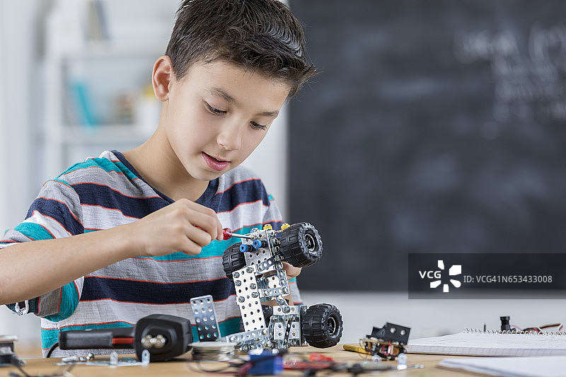 专注组装机器人车辆的小学生图片素材